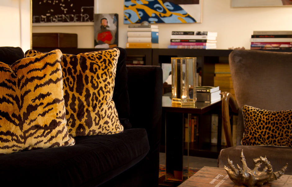 Scalamandre Tigre and leopard pillows with tiger print silk velvet fronts and gold velvet backs on a deep blue couch for contrast.