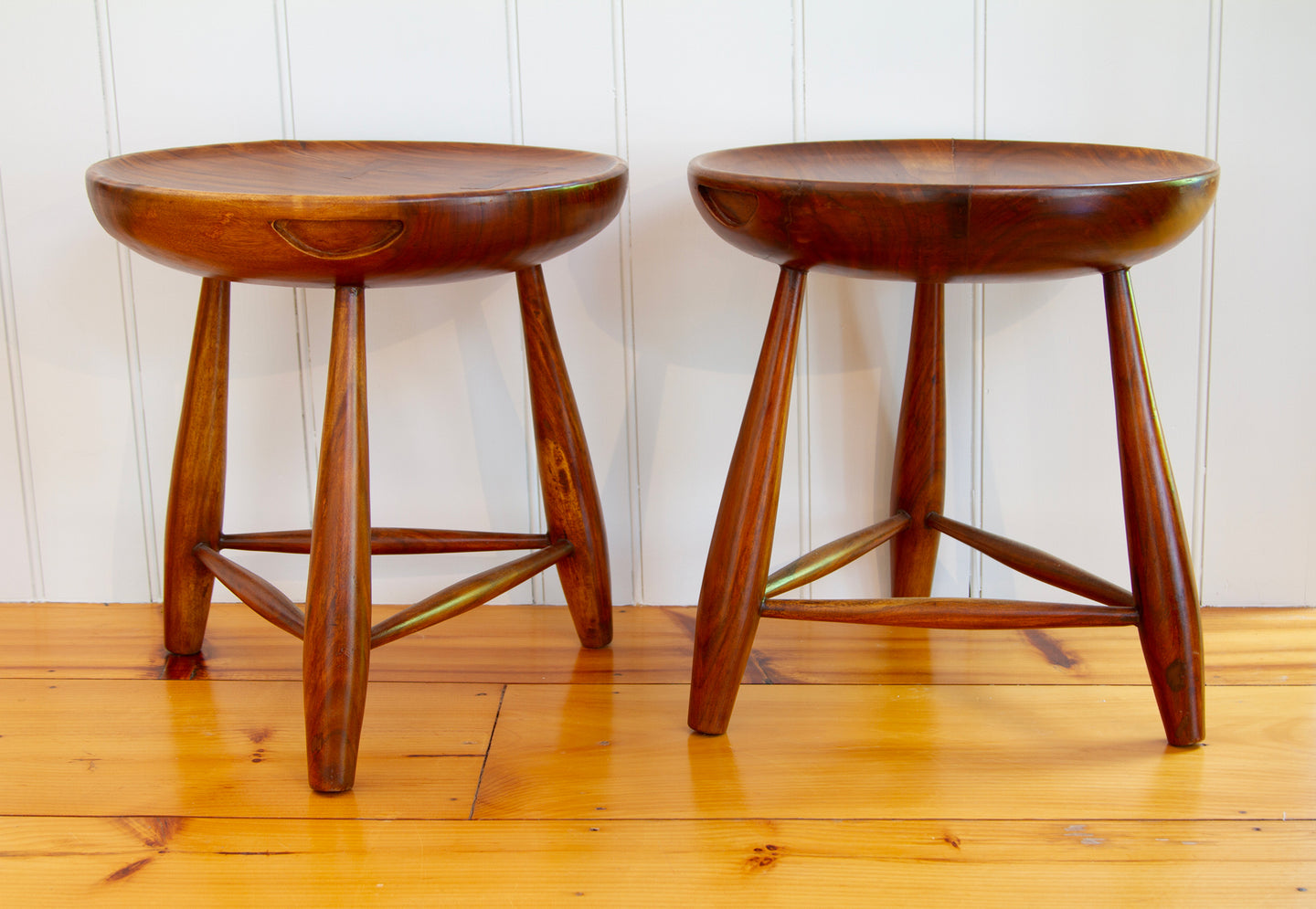Two Walnut three-legged stools with carved handles and concave tops. Used as side tables or seating. 17.5"D x 19" H