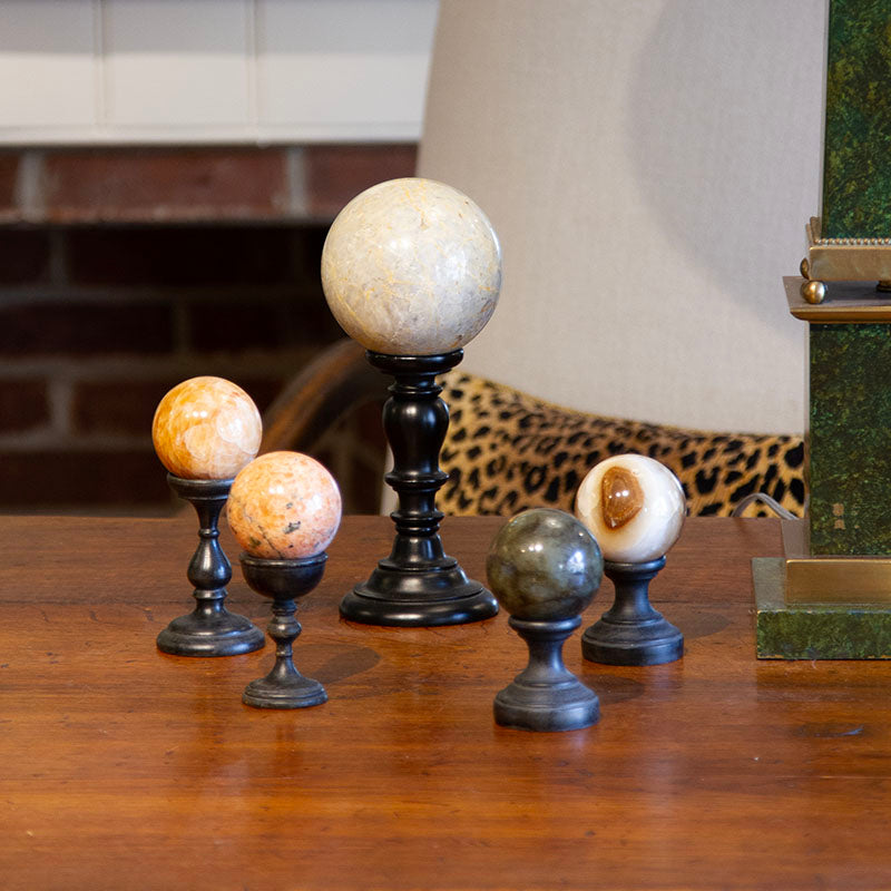 Antique carved stone sphere on a Florentine wooden pedestal with ebonized finish. Small: 4.6” to 6.15” H, Large: 10” H.