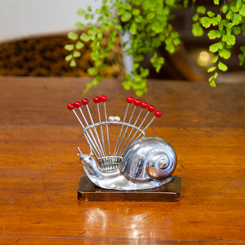 Art Deco snail cocktail pick set made of chrome and wood from the 1940s, measuring 5”W x 2.5”D x 4.5”H.