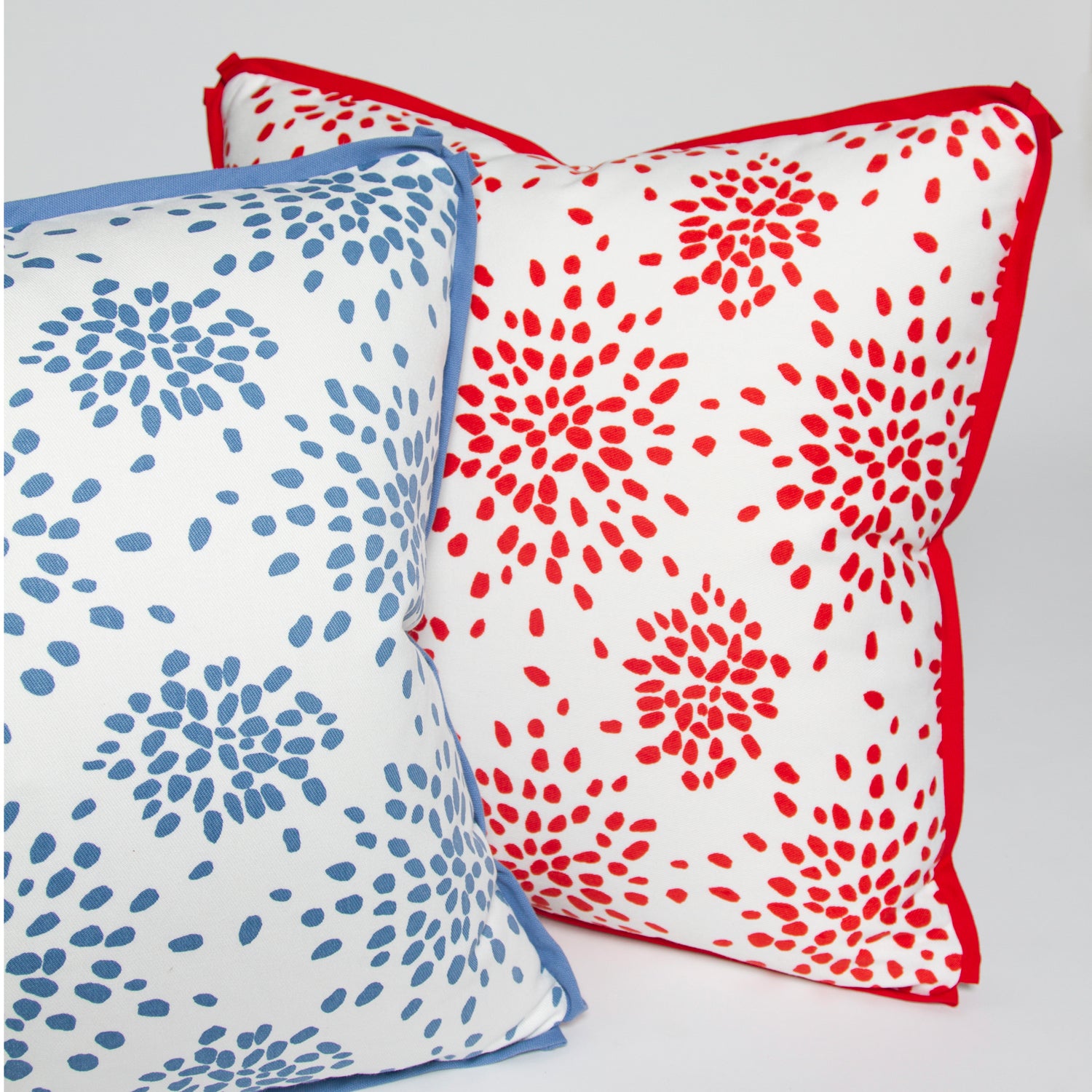 Red and light blue versions of the “Fireworks” pillow by Albert Hadley, both with butterfly flange detail, printed on 100% cotton twill.