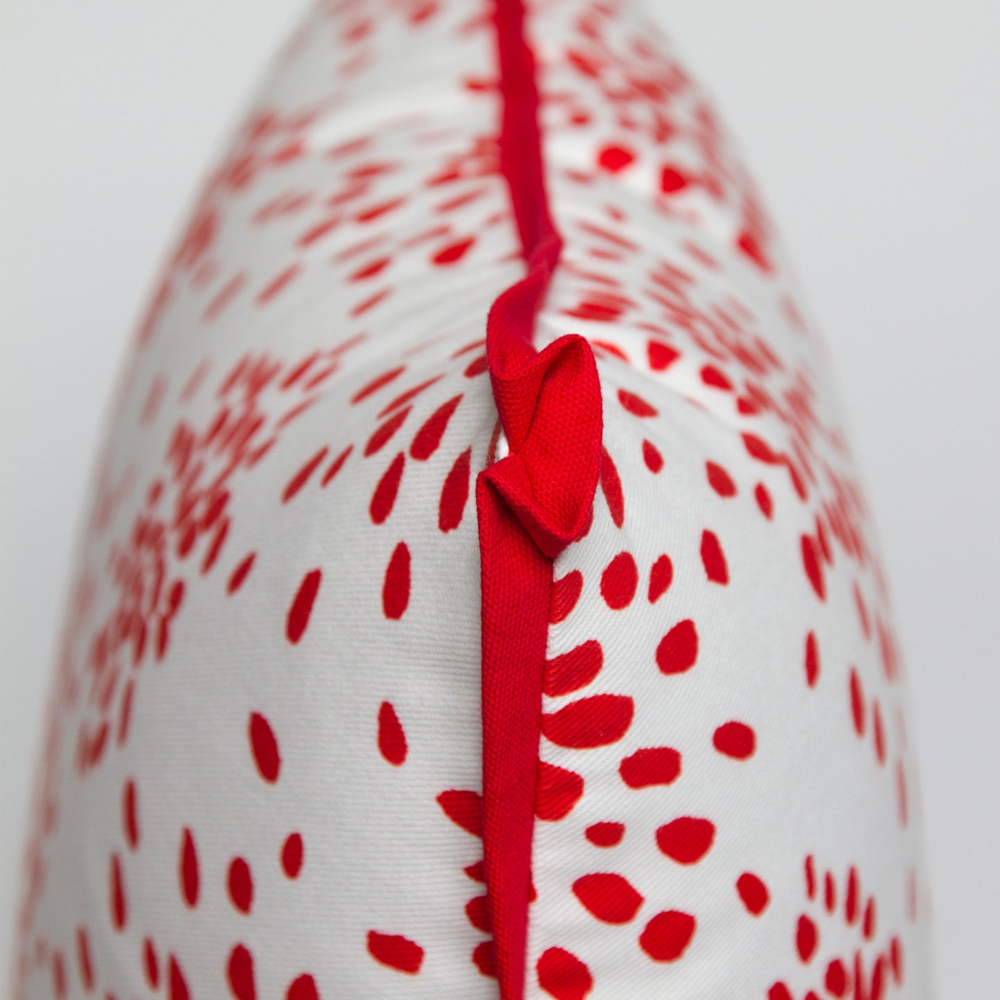 Close-up of the butterfly corner flange detail on the red “Fireworks” pillow by Albert Hadley, showing the contrasting twill.