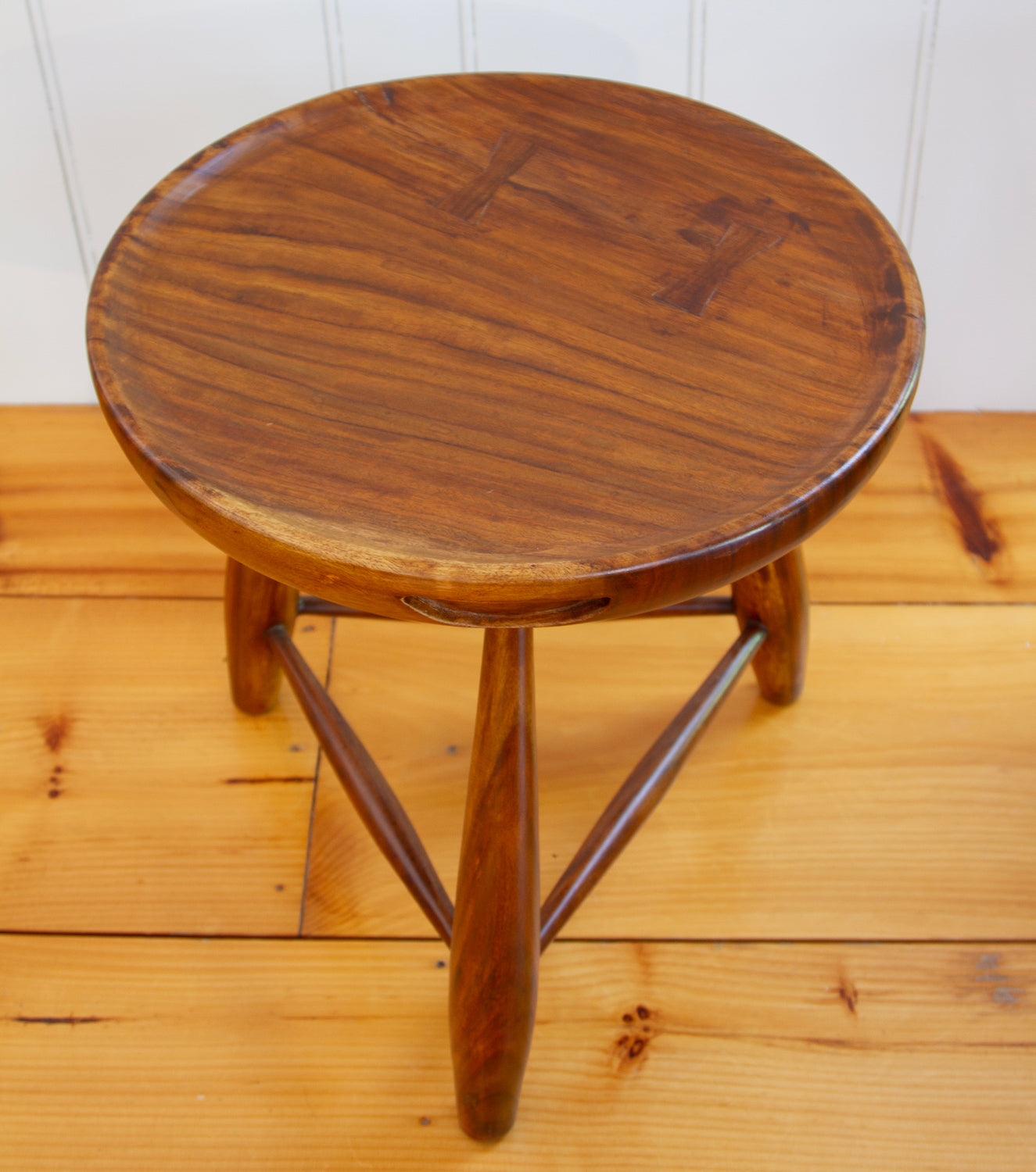 Top view of walnut three-legged stool with carved handles and concave tops.  17.5"D x 19" H