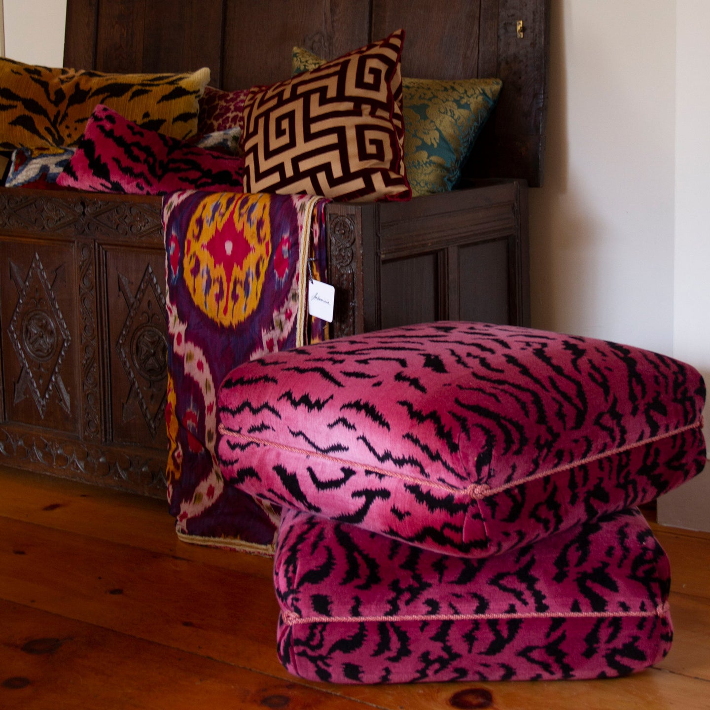 Turkish Ottoman in pink and black tiger velvet, featuring v-pleated corners and knotted trim, 30”L x 30”W x 18”H.