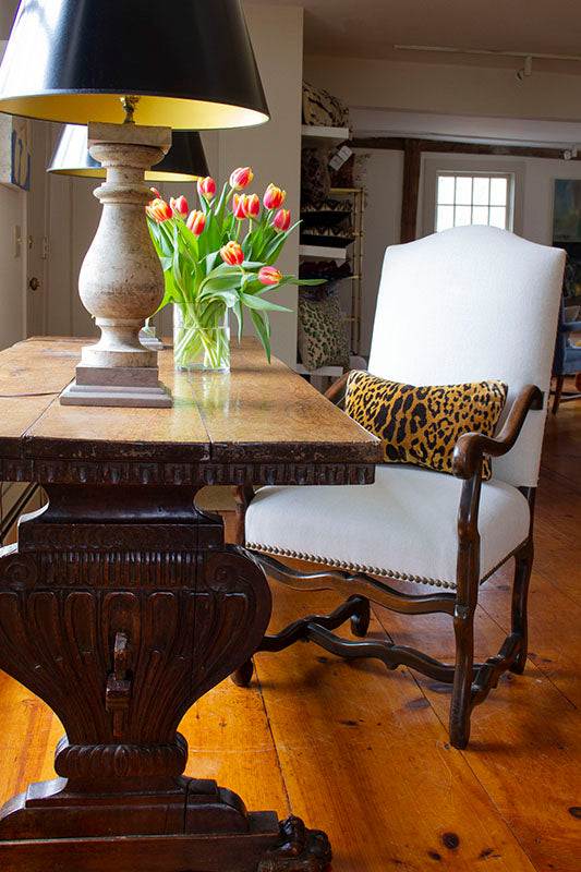 Os De Mouton armchair in natural Belgian linen with brass tacks and dark patinated wood at a desk.