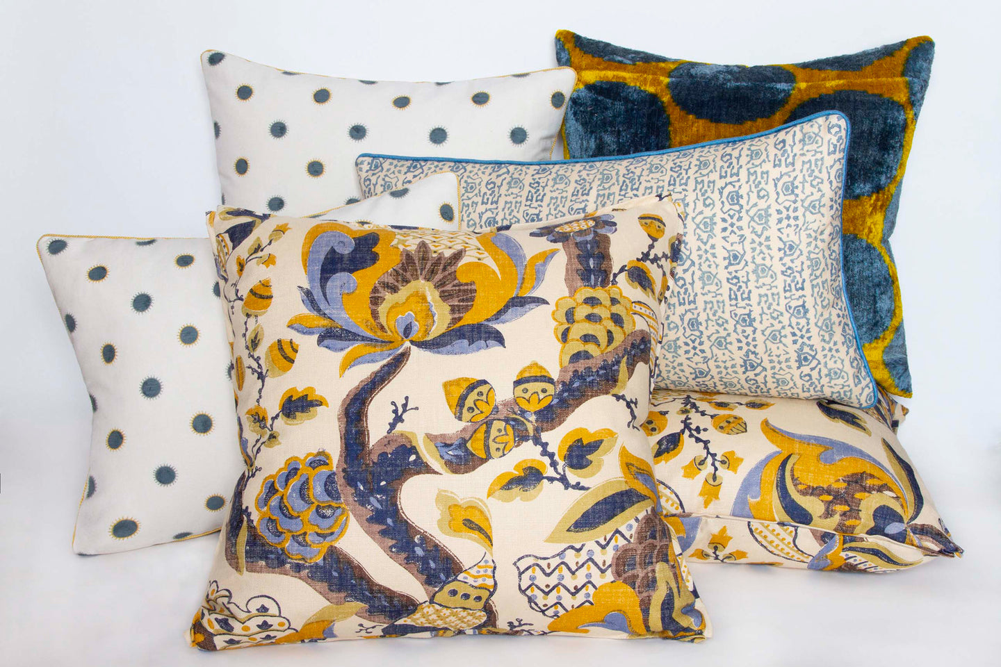 Vibrant saffron and cornflower polka dot ikat pillow in hand-woven silk velvet with other pillows.