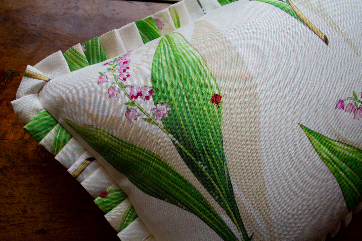 Fabric and pleat detail on Lily of the valley sprig printed on natural linen pillow with a ladybug detail, double-sided.