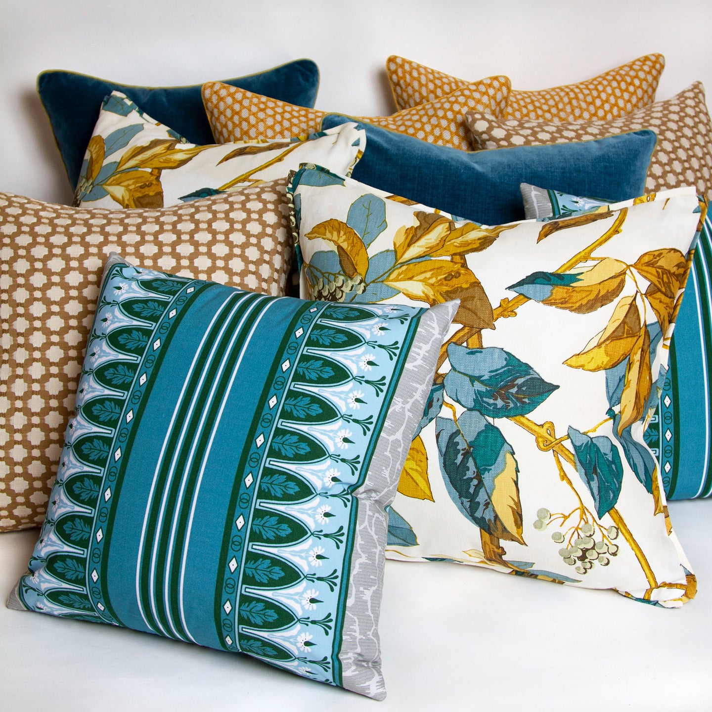 Bold stripes of hunter green, sky blue, and cornflower blue, framed by delicate flowers and oak leaves on 100% cotton percale with other pillows.