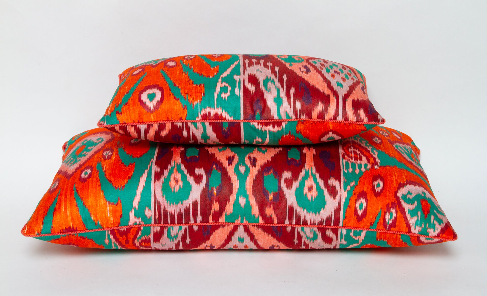 Pierre Frey pillows in bold ikat design featuring tangerine, coral, and teal, available in 10” x 16” or 14” x 24”.