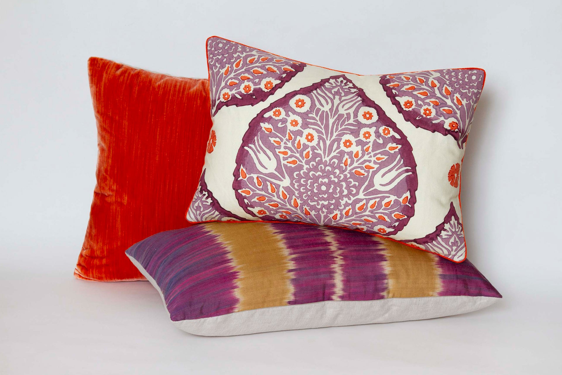 Galbraith and Paul pillow, 14” x 20”, with plum and paprika lotus print on creme linen, purple linen back, and paprika cord with other pillows.