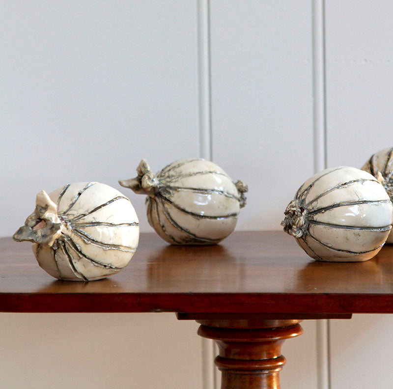 Hand-sculpted ceramic onions in eggshell and gray glaze, measuring 4 to 6 inches in size.