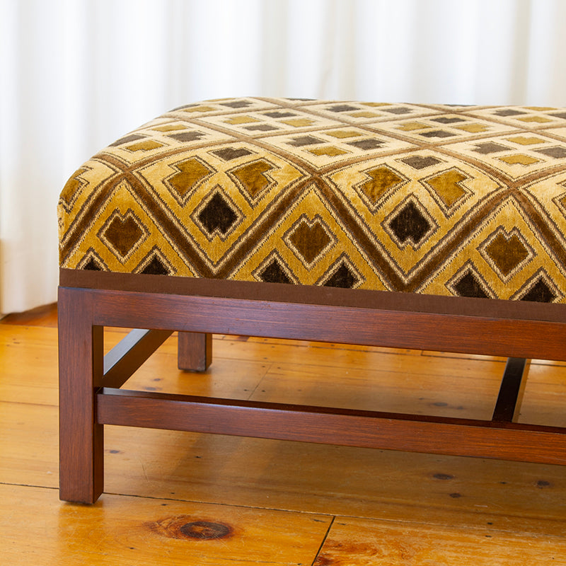 Fabric detail of Ottoman upholstered in sand and cognac Kuba cloth epingle velvet with espresso trim, measuring 42”W x 24”D x 17”H.