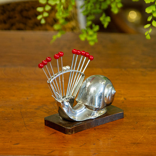 Art Deco snail cocktail pick set made of chrome and wood from the 1940s, measuring 5”W x 2.5”D x 4.5”H.